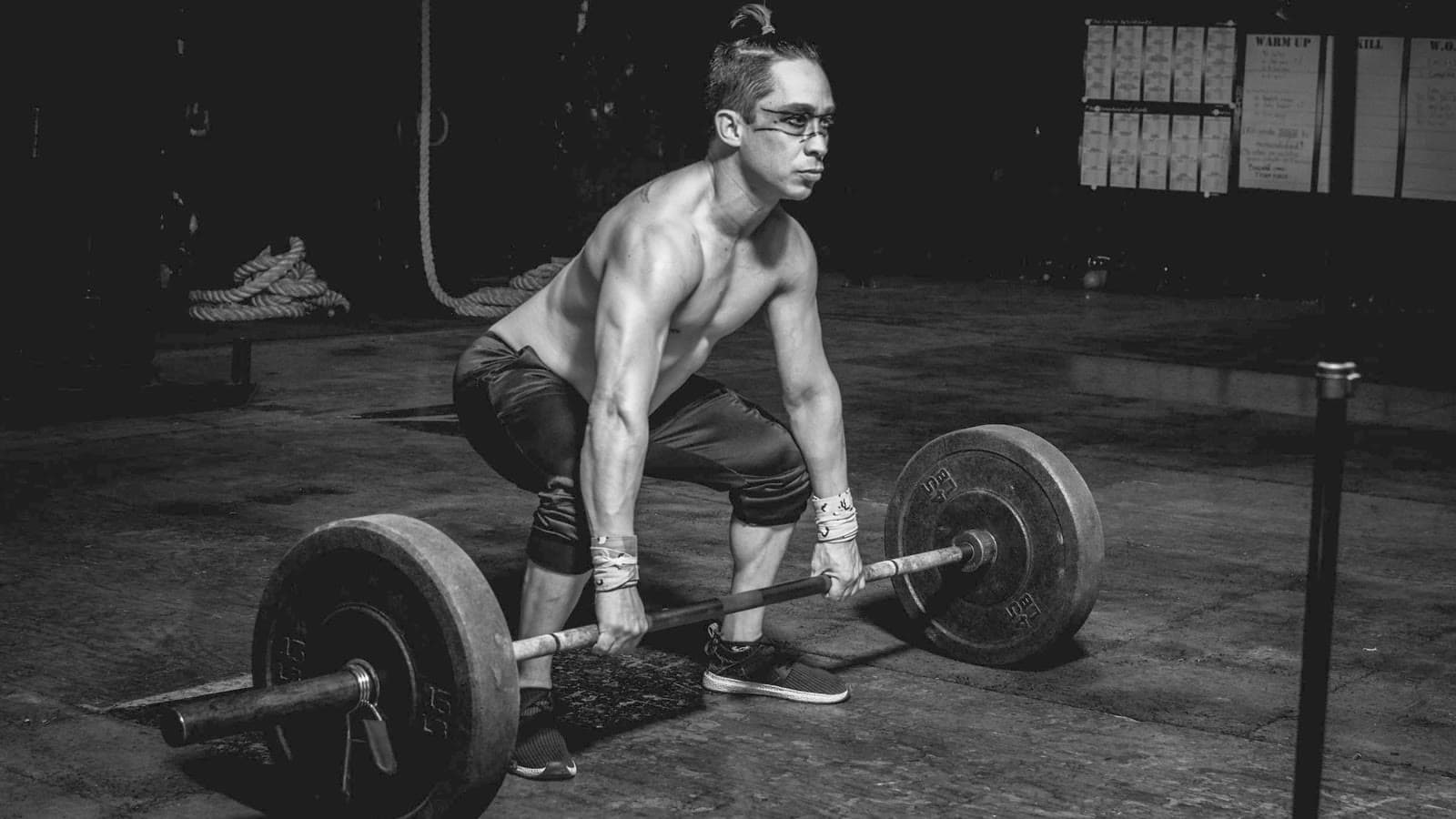 Atleta che solleva un bilanciere in una palestra in penombra